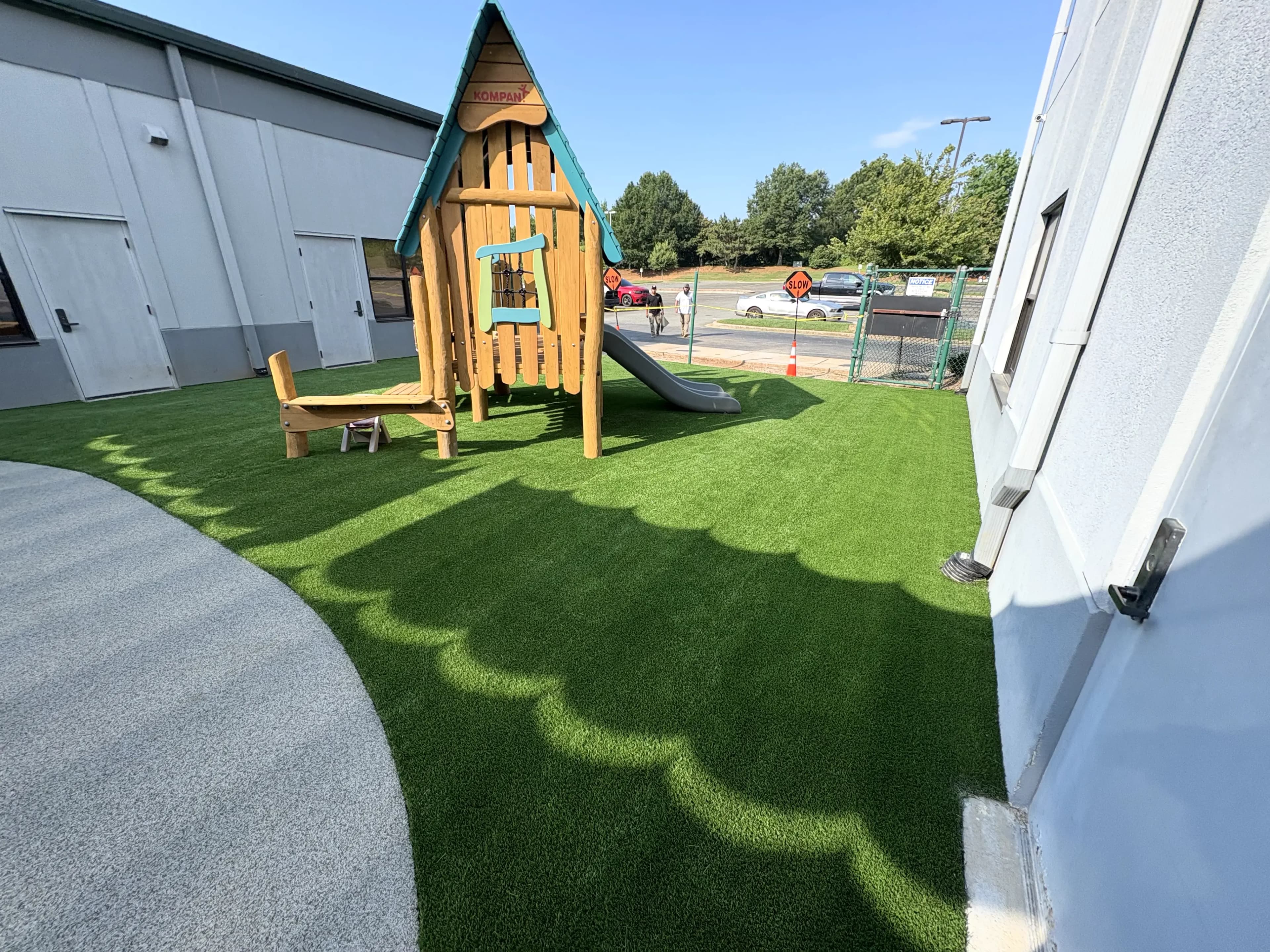 Grace Covenant Church playground turf with KOMPAN playhouse and slide beside rubber safety pathway — Huntersville NC
