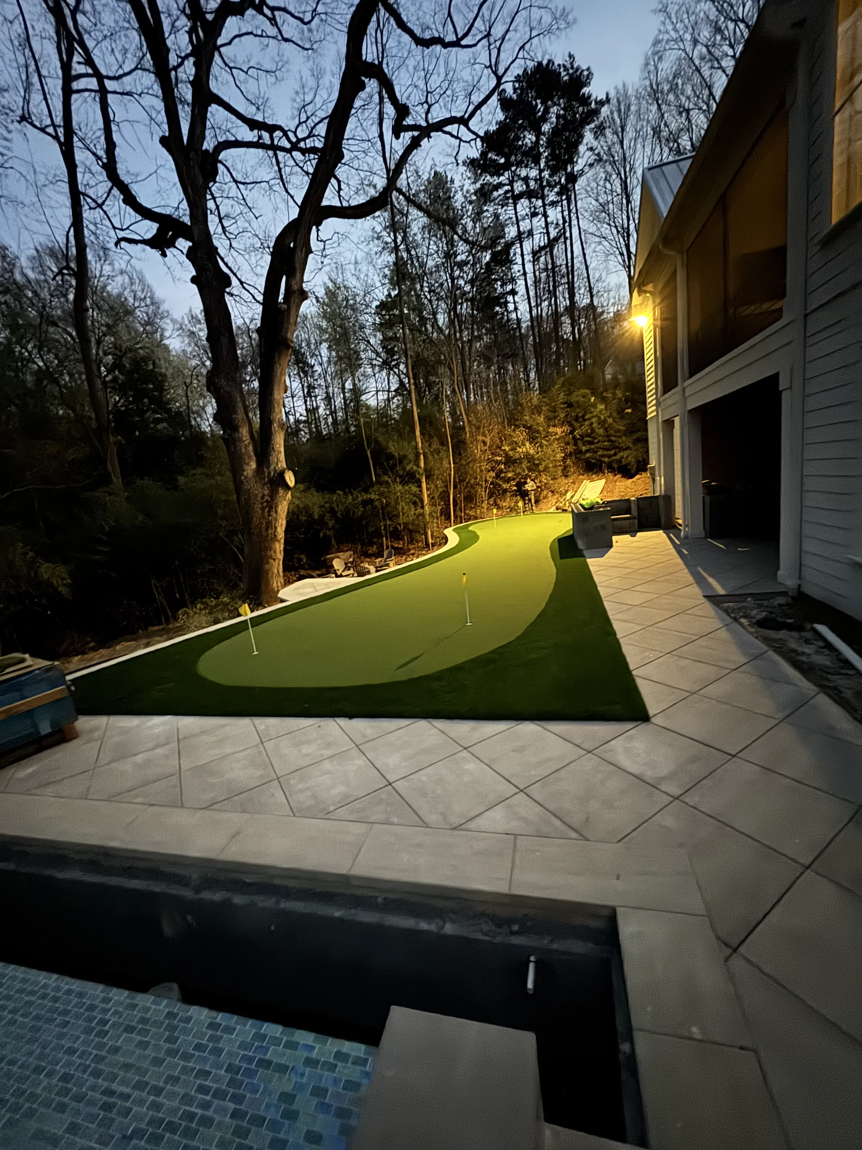 Night-lit putting green beside pool patio — Charlotte NC