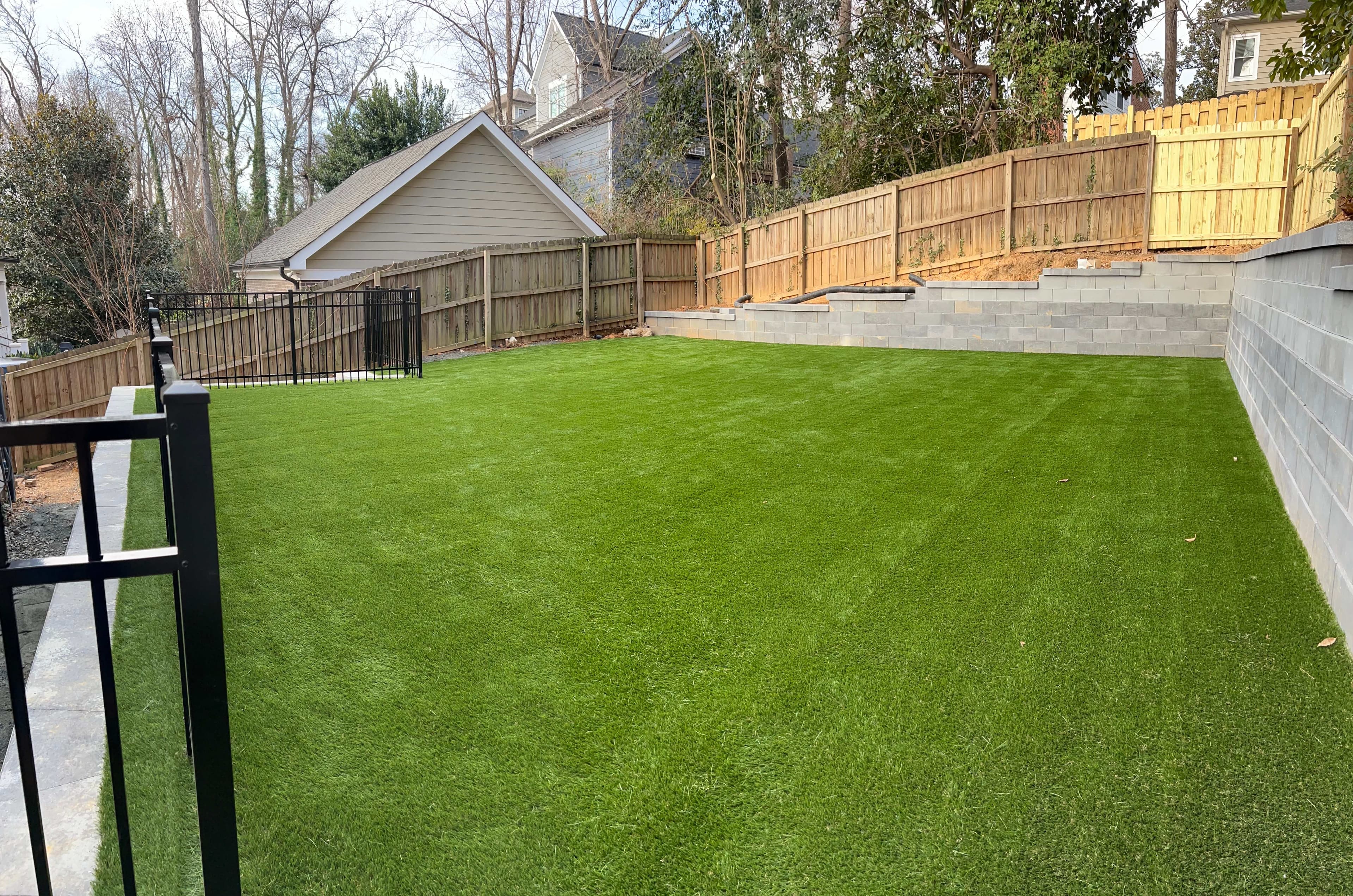 Clean, terraced backyard with privacy fence and artificial turf installation in Charlotte NC
